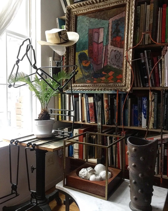 vignette in the new york city apartment of heather karlie vieira of hkfa featuring art and sculpture against a wall of books