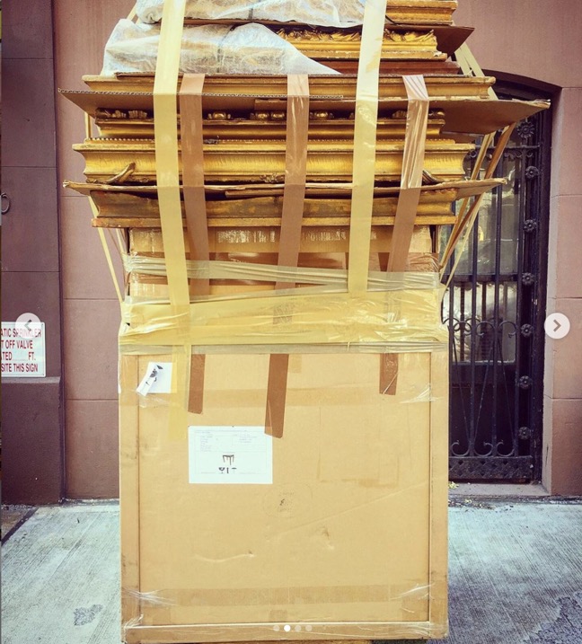 a dolly of antique picture frames on a sidewalk in new york city